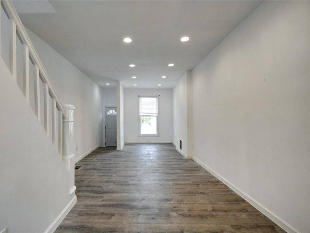 Bright renovated living area with wood-look flooring, stair to upper level, and front door